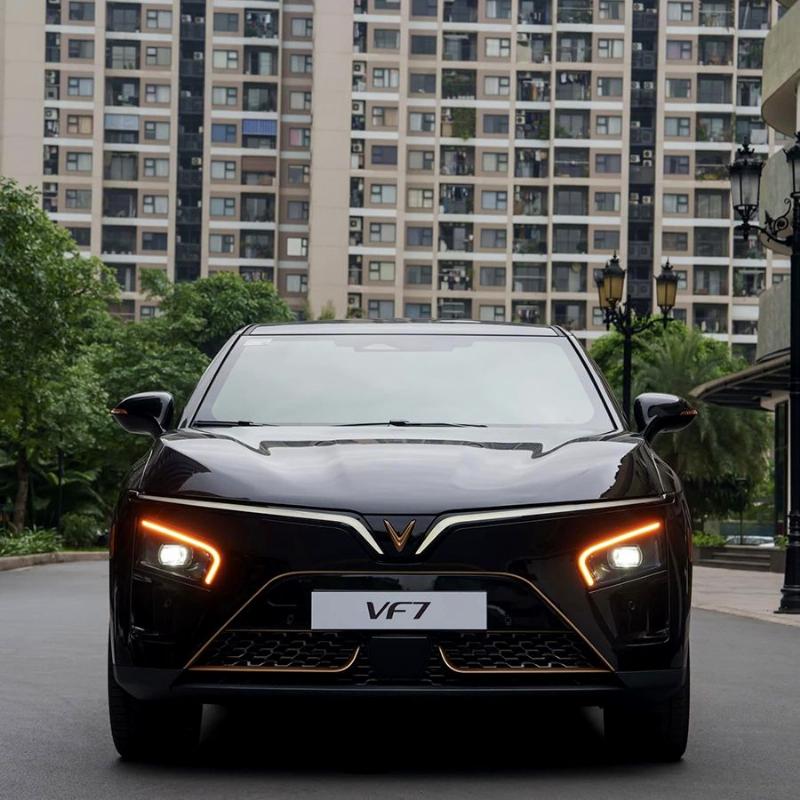 Một xưởng dịch vụ Vinfast rộng rãi, sạch sẽ với nhiều xe đang được sửa chữa/bảo dưỡng. Kỹ thuật viên Vinfast đang làm việc chuyên nghiệp bên cạnh xe, thể hiện dịch vụ sửa xe ô tô gần đây chất lượng cao của hãng.